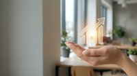 Unrecognizable person holding glowing house icon above palm, symbolizing real estate investment, property ownership, and home security for business and financial concepts.