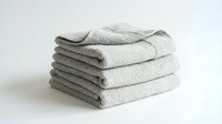 Stack of folded light gray linen towels isolated on white background, ready for home decor, hospitality, laundry service, and textile design projects.