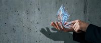 Person in business attire holding glowing digital water droplet against concrete wall, representing sustainable technology, innovation, and environmental solutions.
