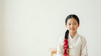 Young East Asian woman wearing traditional white linen shirt with red scarf, smiling at camera against neutral background. Suitable for cultural representation, fashion, portrait, and lifestyle design projects.