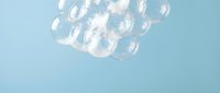 Clear glass bubbles floating against soft blue background, isolated design element suitable for overlays, backgrounds, and creative compositions.