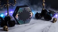Gothic hexagonal box with spider web design surrounded by black roses, candles and skulls on marble surface for Halloween decor and mystical themed projects.