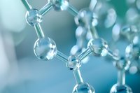 Molecular structure visualization in soft blue and turquoise tones showing connected spherical atoms forming chemical bonds against blurred background.