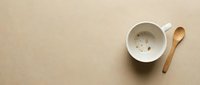 Empty white ceramic mug with wooden spoon on beige background, overhead view. Suitable for coffee shop branding, beverage advertising, and kitchen design projects.