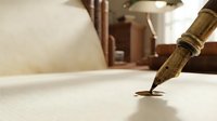 Vintage fountain pen writing on aged parchment paper with antique brass inkwell and quill in background creating elegant calligraphy workspace.