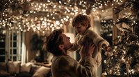 Father and young son sharing tender moment during Christmas celebration with warm bokeh lights and decorated tree creating magical holiday atmosphere at home.