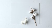 Minimalist flat lay composition featuring white ceramic llama figurine with cotton flower branch on neutral background for design projects.