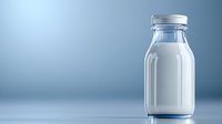 Fresh milk in classic glass bottle with metal cap on blue gradient background, minimalist composition with copy space for dairy product marketing.