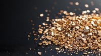 Golden flakes and particles scattered across dark surface, creating luxurious bokeh effect. Suitable for premium branding, cosmetics, and luxury product backgrounds.