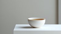 White ceramic cup with hot tea on minimalist white table against neutral gray background, creating clean composition for modern lifestyle content.