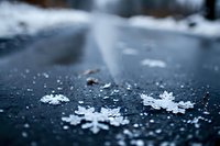 Delicate snowflakes on dark surface with soft blur background create winter atmosphere. Close up macro photography reveals intricate crystalline patterns in natural light.