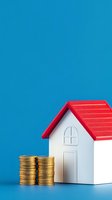 Miniature white house model with red roof and golden coin stacks on blue background representing real estate investment and mortgage savings concept.