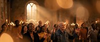 Diverse multiethnic congregation worshipping together in candlelit stone church with dramatic light rays, hands raised in prayer and praise.