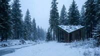 Winter landscape with modern cabin nestled among snow-covered evergreen forest and frozen river, ideal for travel and architecture projects.