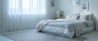 Modern minimalist bedroom interior with gray bedding and soft natural lighting through sheer curtains creating peaceful sleeping space for home decor.