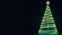Glowing green Christmas tree with golden star and spiral lights on dark background for holiday greeting cards and festive decorations.