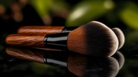 Professional makeup brush with wooden handle and soft brown bristles reflected on black glossy surface against dark background with green foliage bokeh.