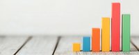 Colorful wooden blocks arranged in ascending bar chart formation on rustic table surface representing business growth, statistics and data visualization.