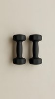 Pair of black dumbbells isolated on neutral beige background, ready for fitness and gym design projects, workout graphics, and health-related marketing materials.