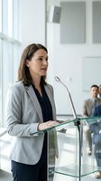 Professional businesswoman speaking at podium during corporate presentation in modern office conference room for business meetings and events.