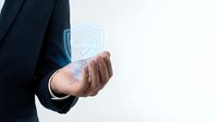 Businessman hand holding glowing digital compliance shield icon representing corporate governance and regulatory protection in modern business.