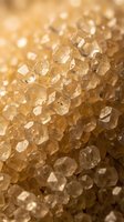 Macro close-up of translucent golden brown sugar crystals with faceted surfaces and soft bokeh background, suitable for food, culinary, and ingredient photography.