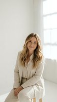Confident blonde businesswoman in beige suit smiling warmly in bright modern office space with natural lighting for corporate and professional use.
