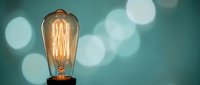 Vintage Edison bulb glowing with warm filament against soft bokeh background for creative lighting design and retro decor projects.