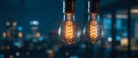 Two vintage incandescent bulbs glow warmly against a blurred urban night skyline, symbolizing innovation, energy, and creative ideas for business and technology concepts.
