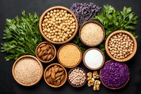 Assorted legumes, nuts, seeds and herbs in wooden bowls on black background. Fresh parsley and purple basil add vibrant color to healthy ingredients.