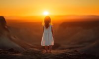 Young woman in white dress standing on desert cliff watching golden sunset over vast landscape creating peaceful silhouette moment for meditation and travel content.