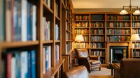 Cozy home library with wooden bookshelves filled with books, comfortable leather armchair and warm lighting creating perfect reading atmosphere for study.