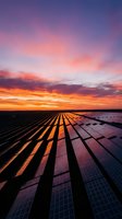 Solar panel array at sunset with vibrant orange and purple sky, renewable energy farm generating clean power during golden hour, sustainable technology landscape.