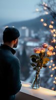 Young man in winter attire gazing at illuminated roses in glass vase against evening cityscape with bokeh lights, creating romantic atmospheric mood.
