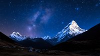 Majestic snow-capped mountain peaks under starry night sky with Milky Way galaxy visible above dramatic alpine landscape for astronomy and nature photography.