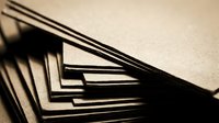 Stack of blank kraft paper sheets with dramatic lighting and shadows creating geometric patterns for packaging and craft projects.