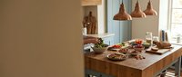Modern kitchen interior with wooden island counter featuring fresh ingredients and copper pendant lights for culinary design projects.