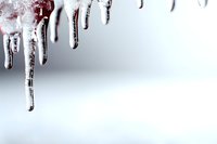 Frozen icicles hanging against blurred winter background, crystalline formations with sharp tips catching light, creating natural abstract pattern in cold weather.