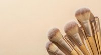 Professional makeup brushes with natural bristles arranged on neutral beige background for beauty and cosmetics applications in salons and personal care.