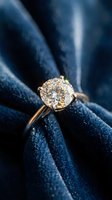 Elegant diamond solitaire engagement ring with brilliant cut stone in gold setting on luxurious blue velvet fabric background for wedding proposals.
