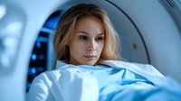 Young female patient lying inside MRI scanner during medical examination procedure in modern hospital diagnostic department. Blue tinted medical environment.