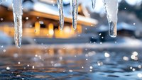 Melting icicles dripping into water with bokeh lights in background creating natural winter scene with sparkling water drops and crystalline formations.
