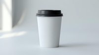 White disposable coffee cup with black lid on clean surface with natural lighting and soft shadows for branding mockup and cafe marketing materials.