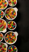 Colorful assorted candies and sweets in white bowls on dark background for party treats, confectionery displays, and dessert presentations.
