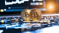 Golden cryptocurrency coins on computer keyboard with reflection and blurred trading chart background, digital money concept for financial technology.