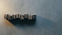 Vintage metal letterpress blocks spelling VARIABLE on textured surface with dramatic lighting and shadows for typography design projects.