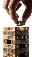 Hand placing wooden block with cryptocurrency symbol on tower of tech-themed blocks representing blockchain, digital finance and investment strategy concepts.