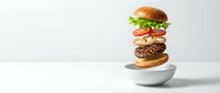 Deconstructed hamburger with floating ingredients above white bowl on clean background for food advertising and restaurant menu design.