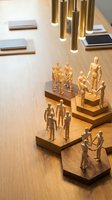 Wooden mannequin figures arranged on stepped platforms under modern pendant lighting showcasing teamwork and collaboration concepts for business presentations.