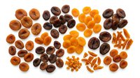 Assorted dried fruits including apricots, dates, and raisins arranged in groups on white background, ready for culinary, nutritional, and food styling applications.